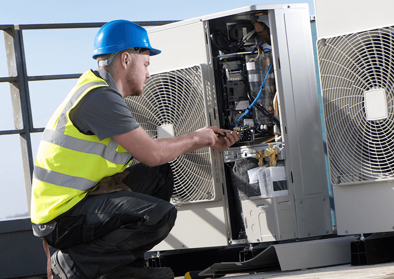 Worker inspecting outdoor air conditioner components